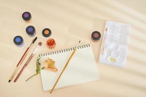 Set of watercolor paint, art brushes and paper on a desk photo