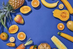 Collection of fresh yellow fruit and vegetables on the blue background photo
