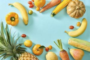 Collection of fresh yellow fruit and vegetables on the light blue background photo