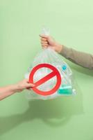 Male hand holding a waste bag isolated on green background. photo