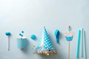 Boy birthday decorations. Blue table setting from above with muffins, drinks and party gadgets. Background layout with free text space. photo