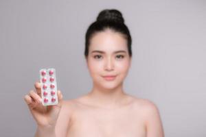 Young woman with pills - focus on pills photo