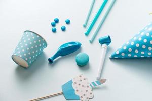 Boy birthday decorations. Blue table setting from above with muffins, drinks and party gadgets. Background layout with free text space. photo