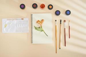 Set of watercolor paint, art brushes and paper on a desk photo