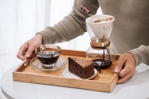 Drip coffee on wooden tray with chocolate cake. Coffee time on the cafe with natural light photo