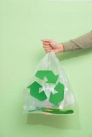 waste recycling, reuse, garbage disposal, environment and ecology concept - close up of rubbish bag with trash or garbage and green recycle symbol at home photo