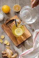 Cup of Ginger tea with lemon. Cup of Ginger tea with lemon. Glass mug of green hot tea on wooden table. Sliced lemons on a chopping board photo