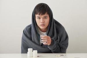 a man wrapped in a warm blanket basks on a light background photo