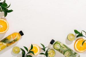 Leaves and bottle tropical water on white background. Detox fruit infused water, citrus fruits and rosemary leaves. Top view, flat lay, copy space photo
