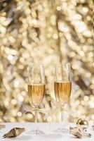 Two full champagne glasses with bokeh lights in the background photo