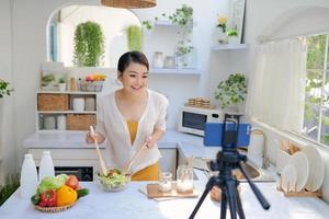 Asian beautiful woman  recording her cooking video using a mobile phone. photo