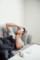hombre enfermo tirado en el sofá que sufre de resfriado y virus de la gripe invernal con tabletas de medicina en el concepto de atención de la salud mirando la temperatura en el termómetro foto