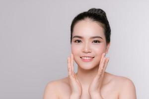 Happy young woman face with clear skin on gray background, closeup portrait photo