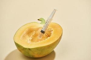 Bright ripe papaya fruit with syringe extracting liquid and showing concept of cellulite treatment photo