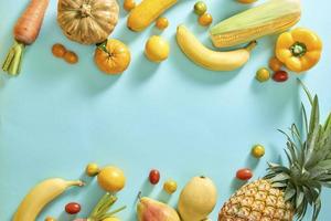 Collection of fresh yellow fruit and vegetables on the light blue background photo