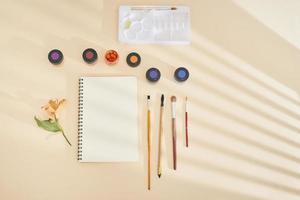 Set of watercolor paint, art brushes and paper on a desk photo