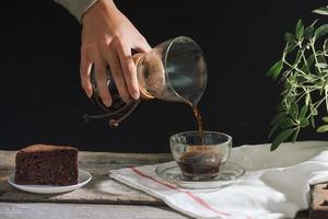 Man pouring cold brew coffee into glass on table photo