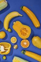 Collection of fresh yellow fruit and vegetables on the blue background photo