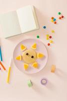 Fun with food concept - Child cooking and eating funny breakfast lion pancake with orange photo