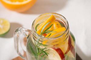 Infused water with lime, orange, apple and rosemary. Cold refreshing detox summer drink .Selective focus photo