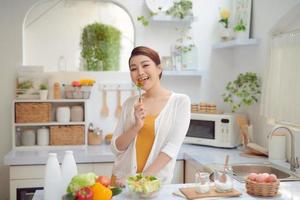 hermosa mujer sonriente comiendo ensalada vegetariana orgánica fresca en la cocina moderna foto