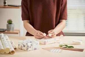 detalle de manos de mujer empacando algunos regalos con papel de regalo foto