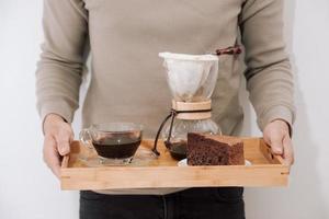 Drip coffee on wooden tray with chocolate cake. Coffee time on the cafe with natural light photo