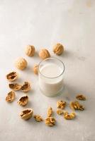 Organic walnut nuts and glass of walnut milk on stone background. photo