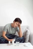 man with headache having in front warm water glass and pills photo