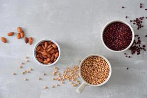 various dried beans with kitchen utensils on gray table, top view photo