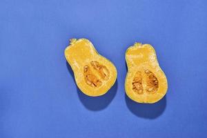 Two halves of ripe butternut squash pumpkin on a blue background. Orange pumpkin with a tail. Close-up photo