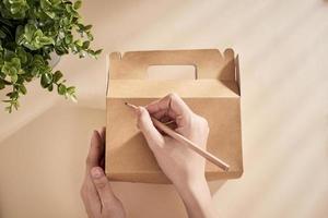 Cropped image of woman writing best wishes on box with present photo