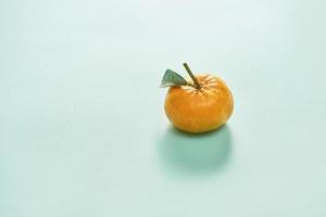 Tangerine or clementine with green leaf isolated on blue background - Image photo