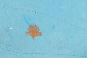 niño sucio dibujando una mancha en la pared azul en casa por una mancha sucia por concepto de limpieza foto