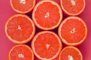 Top view of a several grapefruit slices on bright background in pink color. A saturated citrus texture image photo