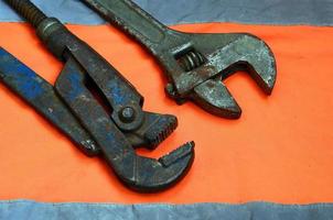 Adjustable and pipe wrenches against the background of an orange signal worker shirt photo