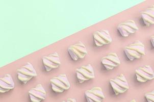 Colorful marshmallow laid out on turquoise and pink paper background photo