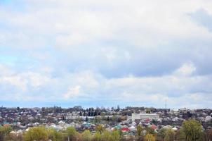 A rural landscape with many private houses and green trees. Suburban panorama on a cloudy afternoon. A place far from the city photo