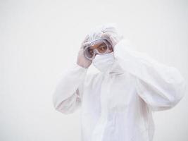 Asian male doctor or scientist in PPE suite uniform In a manner that puts his hand on his head with feeling strees and headache. coronavirus or COVID-19 concept isolated white background photo