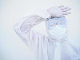 Closeup doctor or scientist in PPE suite uniform holding hand on forehead on white background. COVID-19 concept. photo