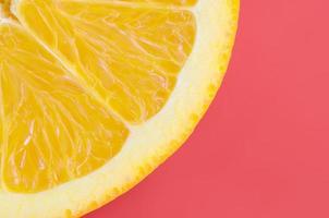 Top view of a one orange fruit slice on bright background in red color. A saturated citrus texture image photo