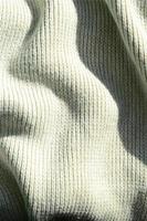 textura de tela de un suéter de punto amarillo suave. imagen macro de la estructura de enlaces en hilos foto