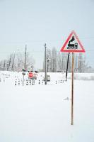 cruce ferroviario sin barrera con muchas señales de advertencia en la temporada de invierno con nieve foto