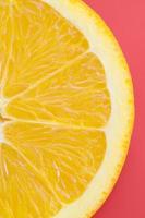 Top view of a one orange fruit slice on bright background in red color. A saturated citrus texture image photo
