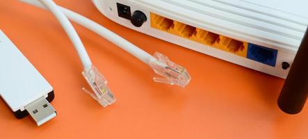 Internet router, portable USB wi-fi adapter and internet cable plugs lie on a bright orange background. Items required for internet connection photo