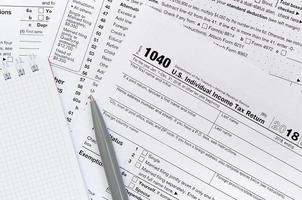 The pen and notebook is lies on the tax form 1040 U.S. Individual Income Tax Return. The time to pay taxes photo