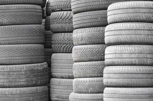 Neumáticos usados viejos apilados con montones altos en el garaje secundario de la tienda de piezas de automóviles foto
