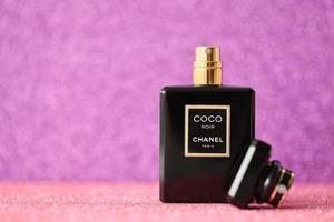 TERNOPIL, UKRAINE - SEPTEMBER 2, 2022 Coco Noir Chanel Paris worldwide famous french perfume black bottle on shiny glitter background in purple colors photo