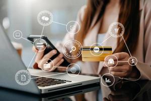 Close up of Hand using credit card and smartphone, laptop computer on wooden desk with VR icon chart graph diagram photo