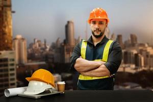 Engineer in helmet for workers security on office buildings and management on the construction drawing plan near laptop working in Engineering tools on desk photo